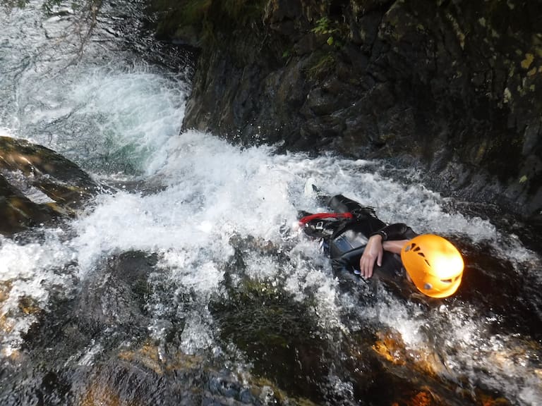 Wasserfall und Schlucht zwischen Felsen mit person beim Abseilen während des Canyonings
