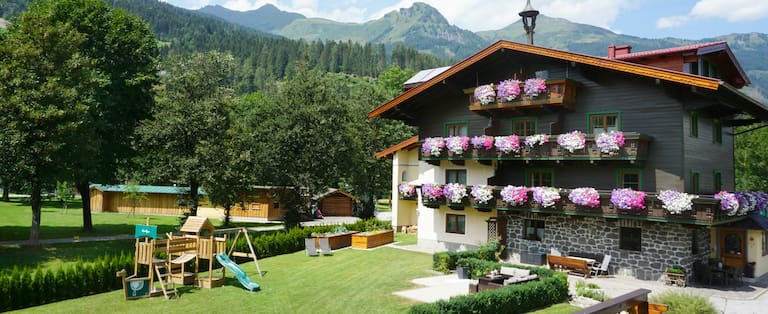 Bio Bauernhof Kendlgut in Badhofgastein umringt von Bäumen und Bergen im Hintergrund