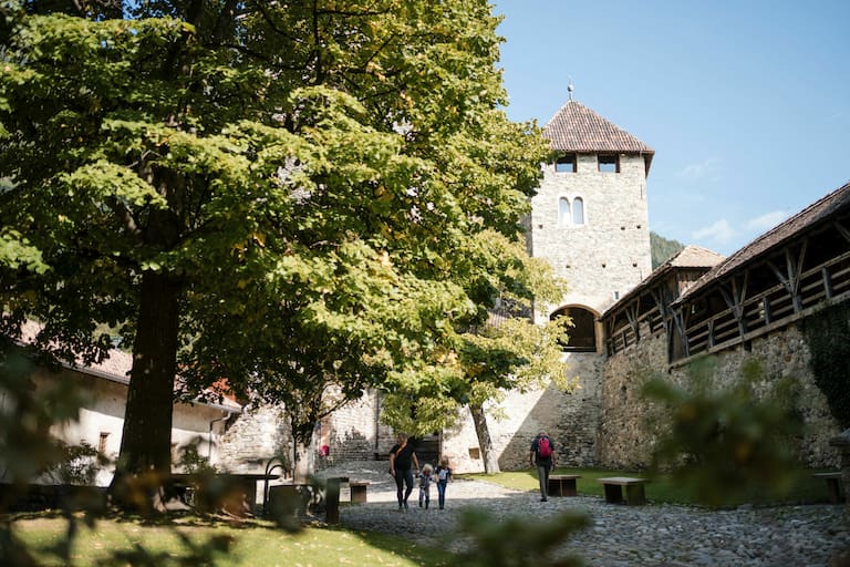 Das Schloss tirol in Südtirol mit Bäumen und Wanderern